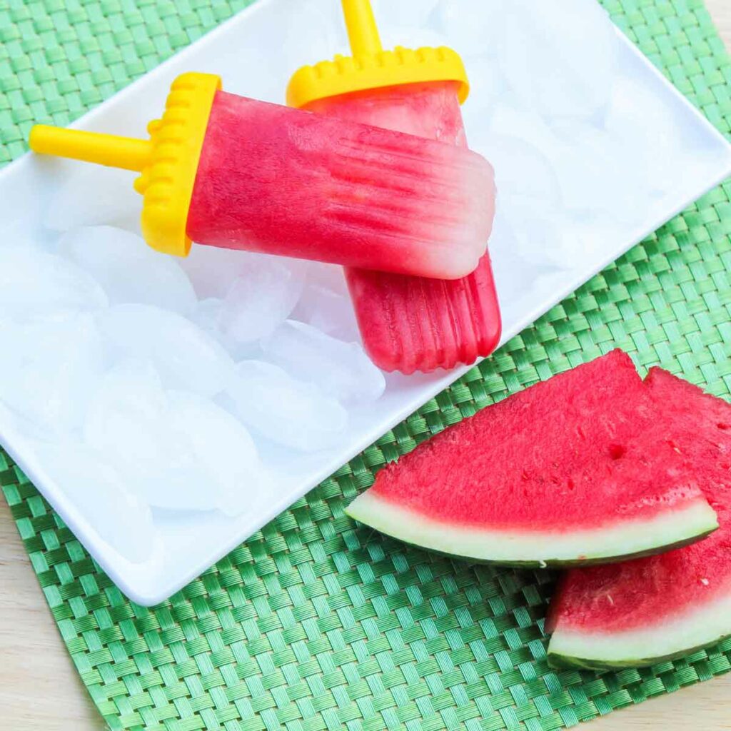 Real Fruit Watermelon Lime Popsicles on a plate of ice with two slices of watermelon