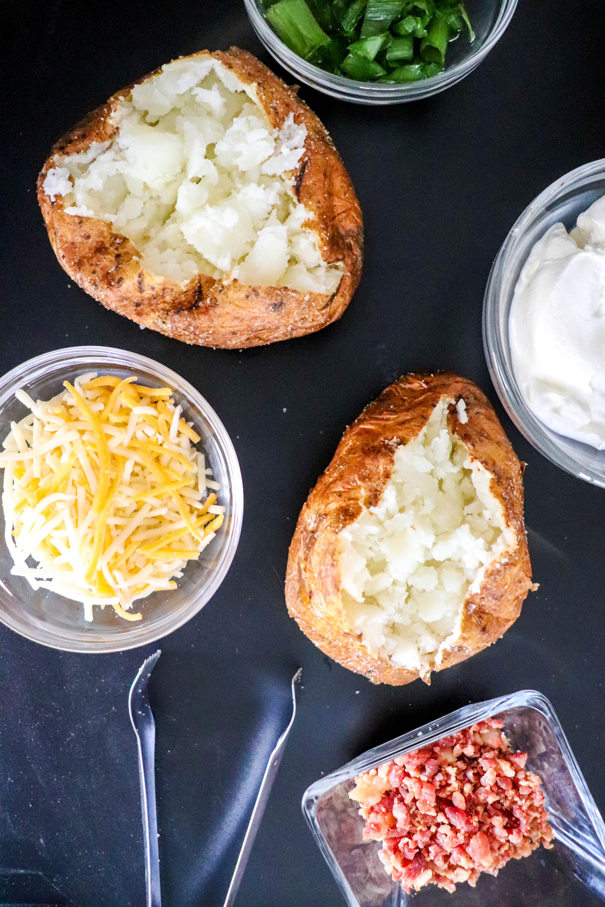 Air Fryer Baked Potatoes Fluffy Insides Exposed surrounded by optional toppings
